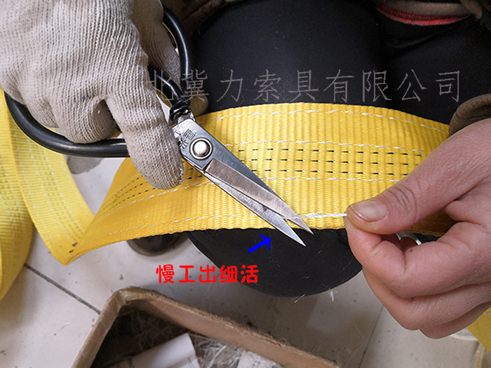工人正在给吊装带织带修剪线头