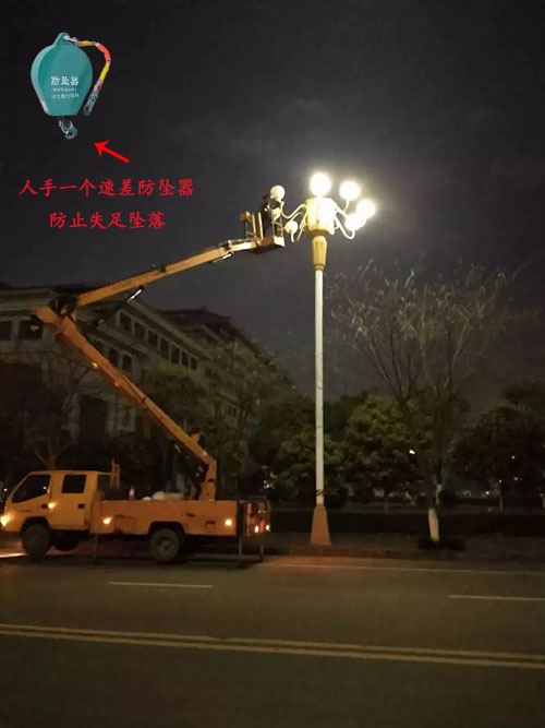 夜晚工人佩戴速差防坠器进行高空维修路灯